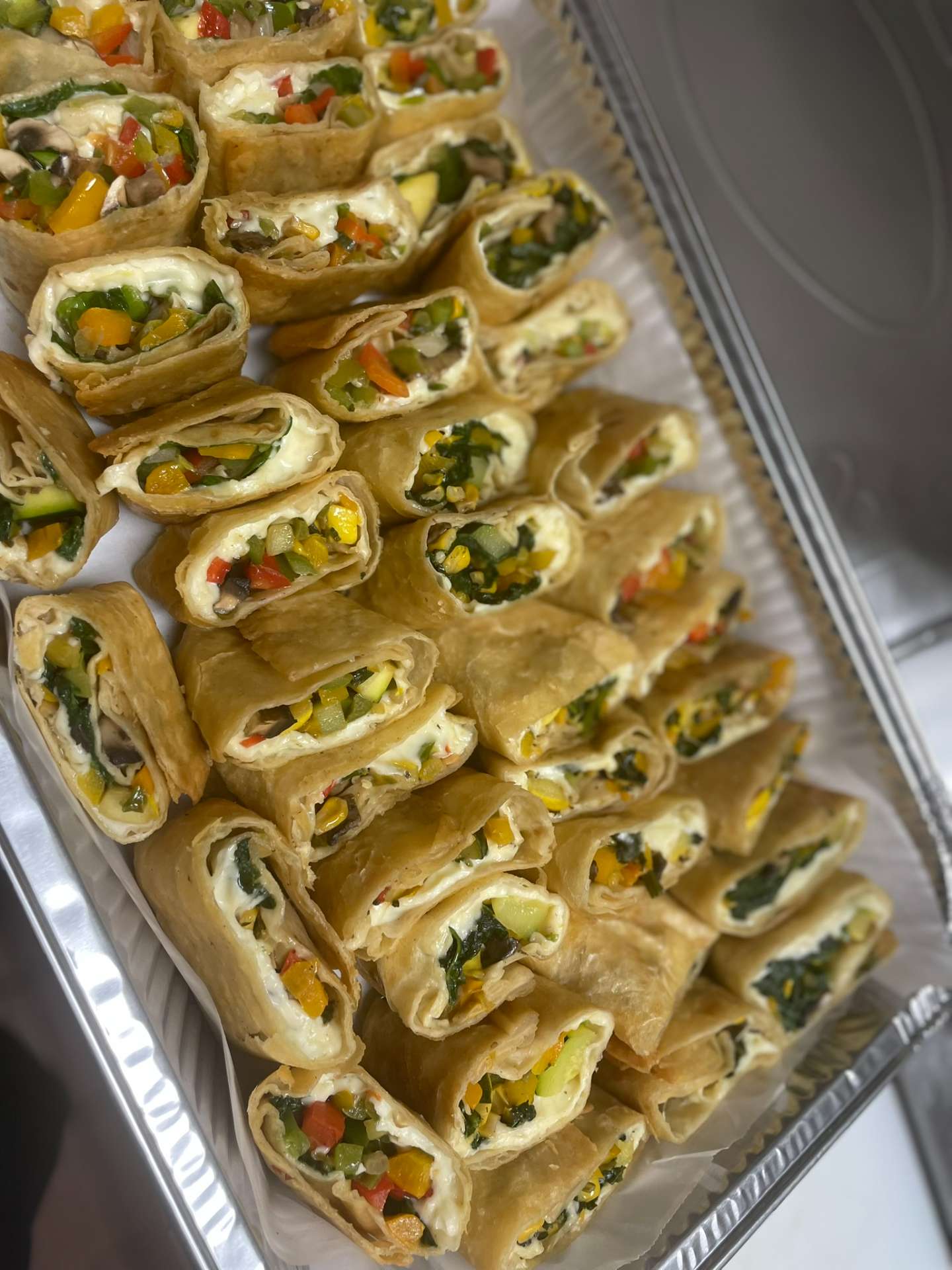 Catering tray of fresh vegetable appetizer wraps with peppers and greens from Cafe Mona Stillwater.