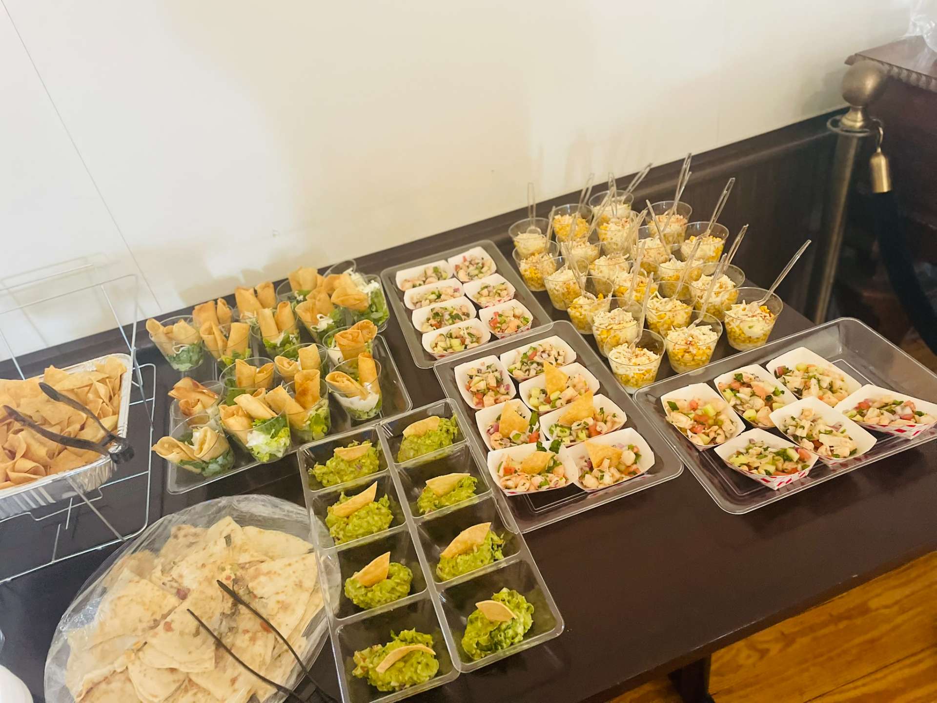 Mexican catering appetizer spread with guacamole cups, taquitos, shrimp ceviche boats, and elote cups from Cafe Mona.