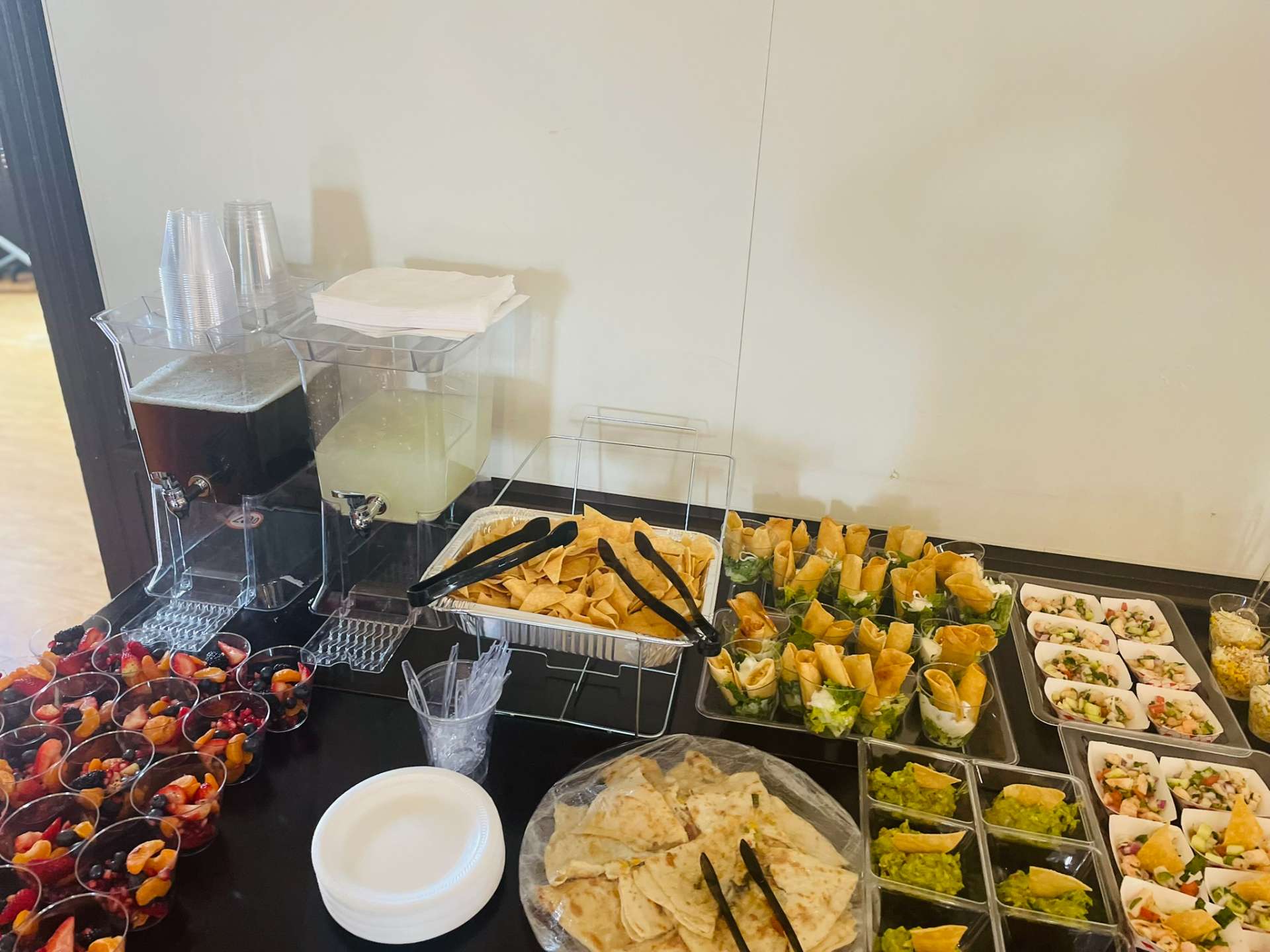 Full Mexican catering buffet with guacamole cups, quesadillas, tortilla chips, and fresh fruit at Cafe Mona in Stillwater, Oklahoma.