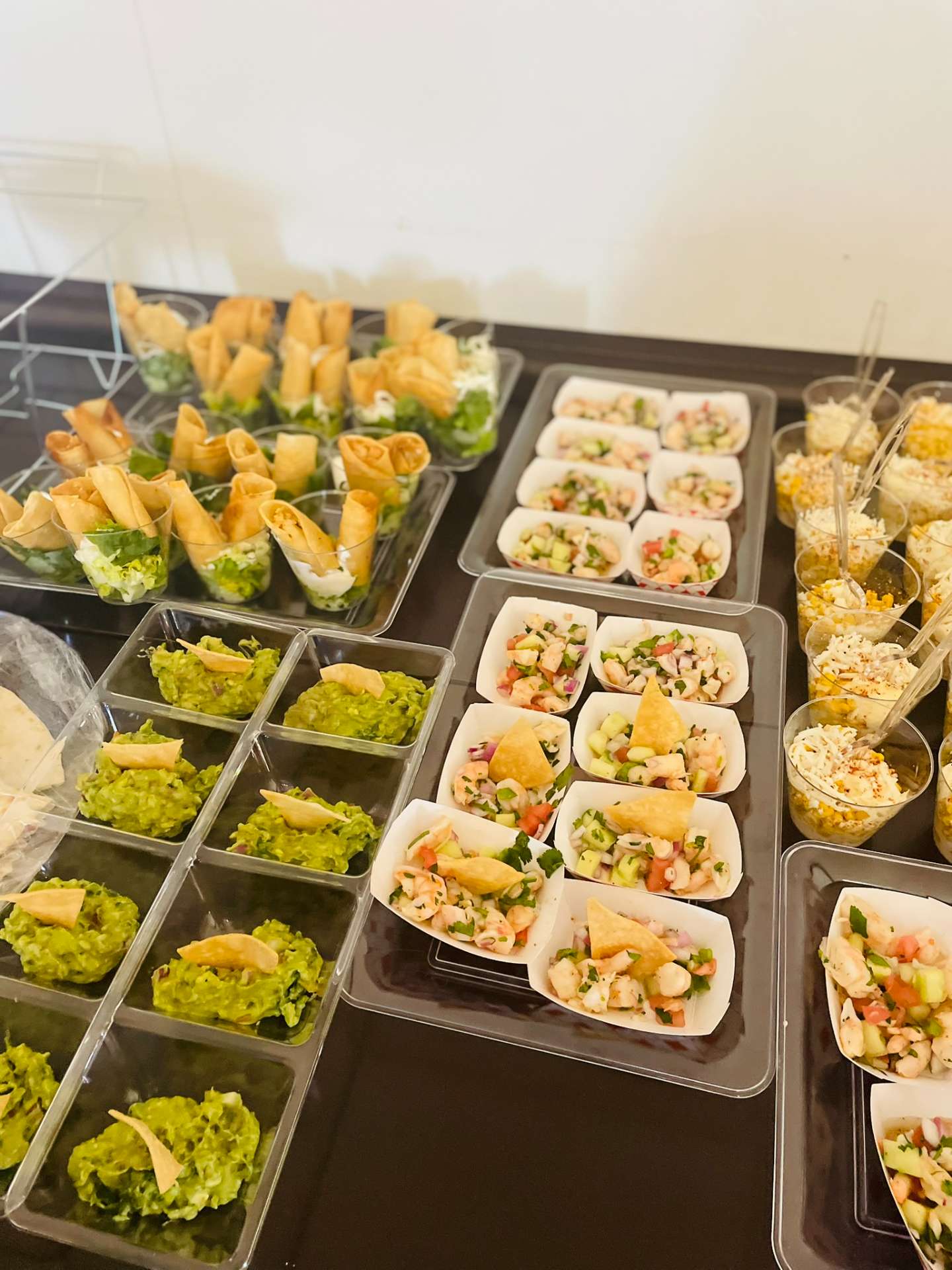 Catering trays of taquito cups, guacamole with chips, shrimp ceviche boats, and elote cups from Cafe Mona Stillwater.